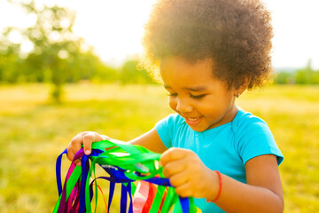 multicultural little girl with curly afro hair making a gift for parent by herself outdoor shot
