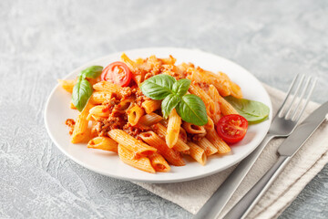 Pasta Penne Bolognese in white plate on light background. Bolognese sauce is classic italian...