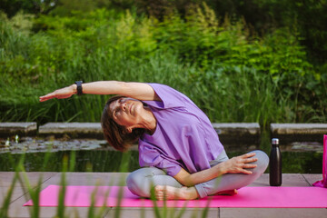 An old slender woman does yoga in the park