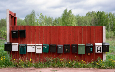 row of different letter boxes on a wooden red wall in the open at Sweden