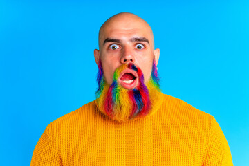 cool man with colorful beard looking at camera and feeling amazing in studio blue background
