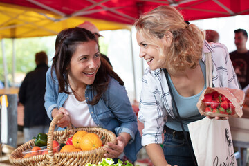 young women buying fruits at city market