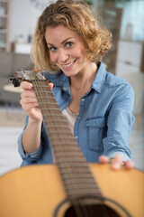 woman holding an acoustic guitar to check it