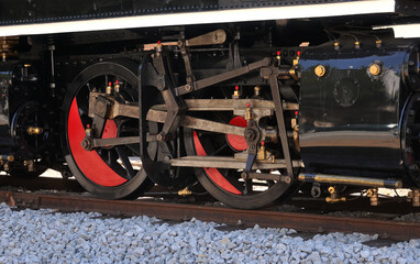 Mecanismo de braços e rodas de uma locomotiva a vapor parada em cima de carris - obrazy, fototapety, plakaty