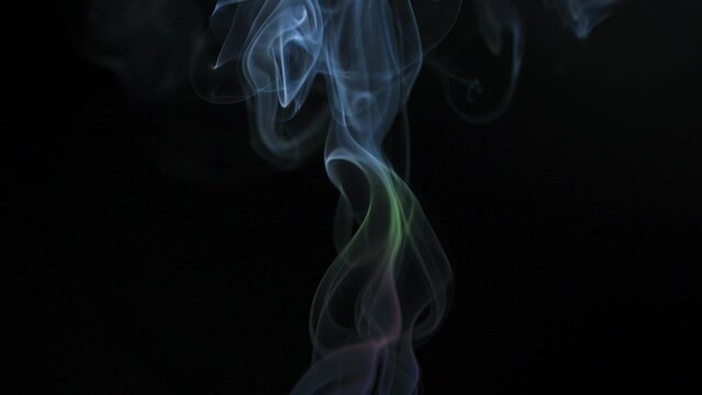 Abstract colored smoke rises up in beautiful swirls on a black background. Slow motion