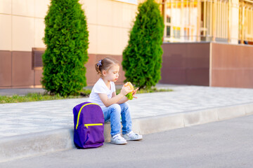 child schoolgirl eats lunch or snack burger before school, concept back to school or school meals