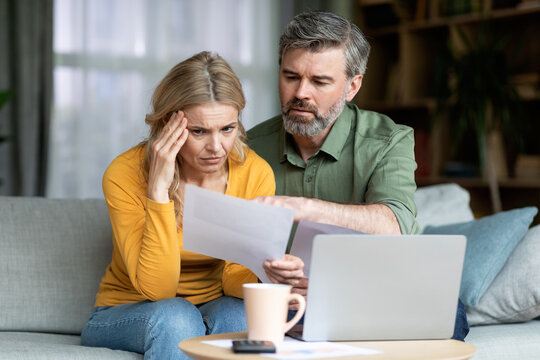 Stressed Middle Aged Spouses Checking Financial Papers At Home