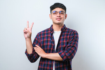 Young handsome asian guy doing peace symbol with fingers over face, smiling cheerful showing victory