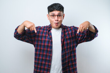 Naklejka premium Young handsome man pointing down with fingers showing advertisement, surprised face and open mouth