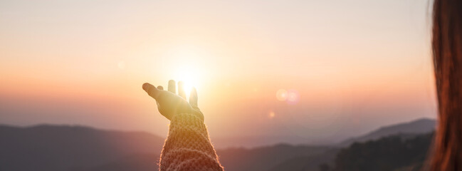 Young woman hand reaching for the mountains during sunset and beautiful landscape - obrazy, fototapety, plakaty