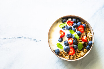 Greek Yogurt with granola and fresh berries at marble table. Top view with copy space.