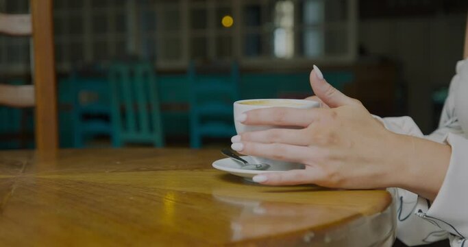Cute girl drinking coffee in restaurant, cafe. Girl hands with coffee
