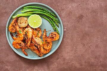 Grilled shrimp (tiger prawns) in spices with asparagus and a slice of lime (lemon) on a plate on a...