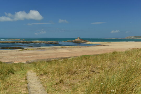 St Ouen’s Bay, Jersey, U.K. Summer natural beach with Rocco tower at mid tide.