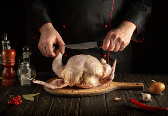 Professional chef cuts raw broiler chicken with a knife. Cooking a national dish in the kitchen with chicken