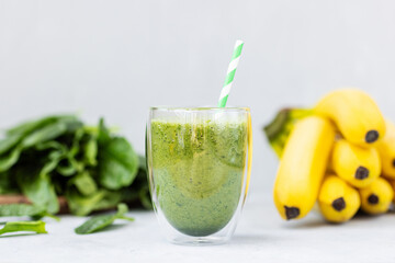 Vegetarian green smoothie with avocado, spinach leaves, banana in glass on gray concrete background. Raw, vegan, vegetarian, alkaline food, Healthy Lifestyle detox concept. Selective focus.