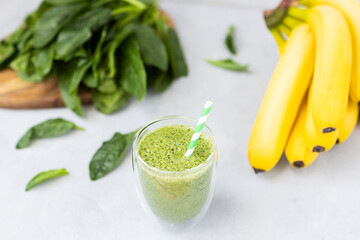 Vegetarian green smoothie with avocado, spinach leaves, banana in glass on gray concrete background. Raw, vegan, vegetarian, alkaline food, Healthy Lifestyle detox concept. Selective focus.