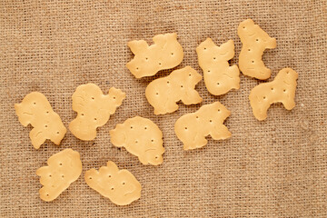Several homemade zoological cookies on jute fabric, close-up, top view.