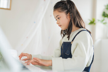 部屋でピアノを弾く女の子 © One