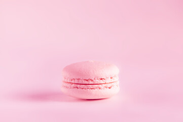 One pink macaroon on the same background. Selective focus with copy space