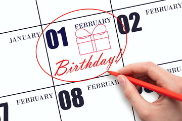 The hand circles the date on the calendar 1 February, draws a gift box and writes the text Birthday. Holiday.