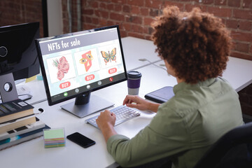 Biracial businessman researching on nfts while working on desktop pc in office