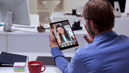 Rear view of caucasian businessman video conferencing with female colleague over digital tablet