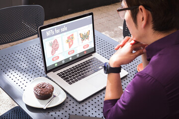 Aziatische zakenman analyseert nft over laptop terwijl hij met cupcake op terras zit