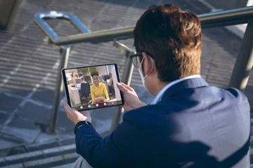 Foto op Plexiglas Aziatische plekken Aziatische zakenman die een masker draagt tijdens een videoconferentie op een digitale pc terwijl hij buiten zit