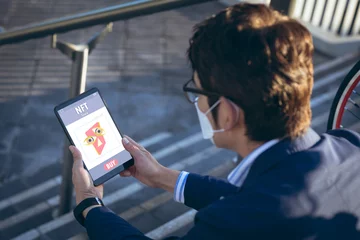Foto op Plexiglas Aziatische plekken Aziatische zakenman die een masker draagt en onderzoek doet naar nft via digitale tablet terwijl hij op trappen zit