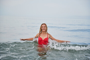 a girl in a red swimsuit laughs at sea