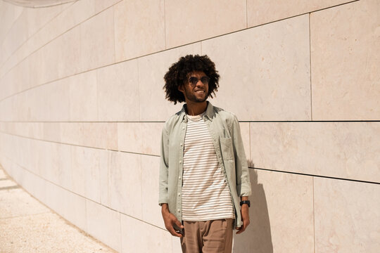 Happy Black man outdoor. African American man in casual clothes and sunglasses walking on sunny day. Portrait, city life concept