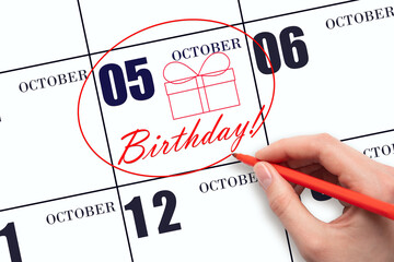 The hand circles the date on the calendar 5 October, draws a gift box and writes the text Birthday....