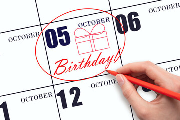 The hand circles the date on the calendar 5 October, draws a gift box and writes the text Birthday. Holiday.