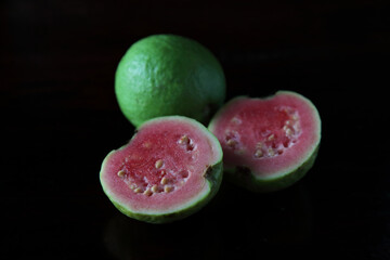 Guava fruit and its slices on dark background.