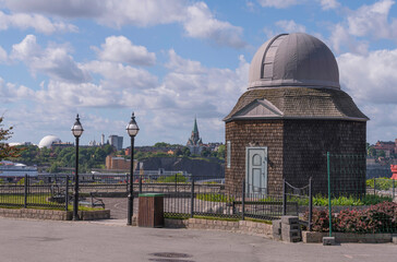 Old small wooden star observatory from early 1900s with the district Södermalam and the globe Avicii, Globen arena in the background in a park a sunny day in Stockholm