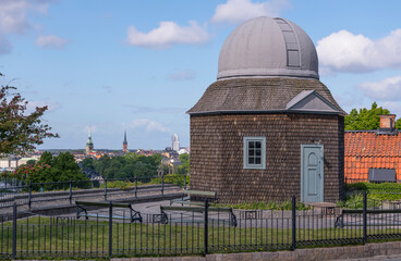 Old small wooden star observatory from early 1900s with the old town Gamla Stan churches in the background in a park a sunny day in Stockholm