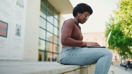 Side view of attractive female freelancer working on laptop on t