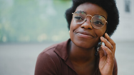 Close up African girl in glasses smiling looking away while talk