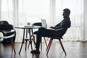 young business man working on a laptop while sitting at a coffee table.
