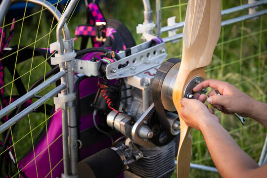A male pilot unscrews a broken wooden propeller of a gasoline powered paraglider after a failed landing. Paragliding for individual paragliding flights. Extreme sports.