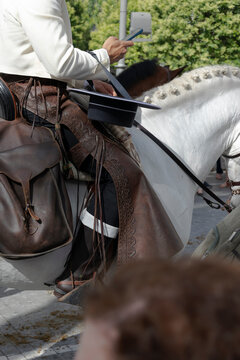 Detail of the hand of a rider manipulating his mobile and his Zahon in the traditional outing of the brotherhood of Rocio de Huelva in Spain