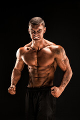 Fototapeta na wymiar Handsome power athletic man confidently looking forward. Strong bodybuilder with six pack, perfect abs, shoulders, biceps, triceps and chest Isolated on black background