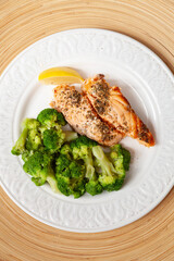 Grilled salmon served with broccoli and a piece of lemon on white plate. Vegetarian lunch for diet.