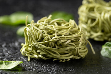 Dry spinach noodles on rustic dark background