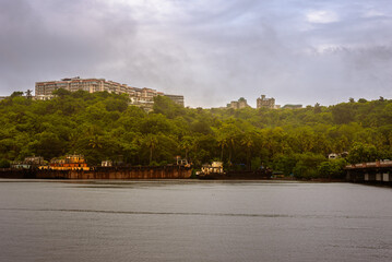 Fototapeta premium Beautiful monsoon landscape in Goa India from the San Jacinto island with ship building activities and barges docked on the port.