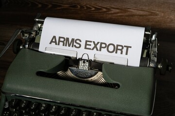 Arms export is written in large letters on a white piece of paper on an old army green typewriter.
