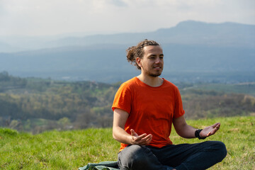 Naklejka na ściany i meble Young man meditating yoga on the rock peak. Relax and calm