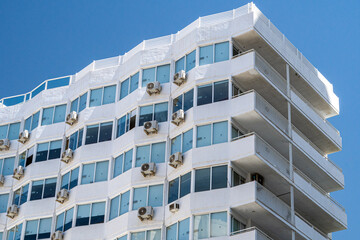 Modern glass building, with air conditioners ,against blue sky. - obrazy, fototapety, plakaty