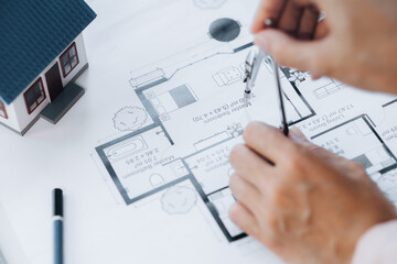 A building and house architect is reviewing and revising the house designs of a large housing project, he draws roundabouts on the house plans. Home and interior design ideas by architect engineers.